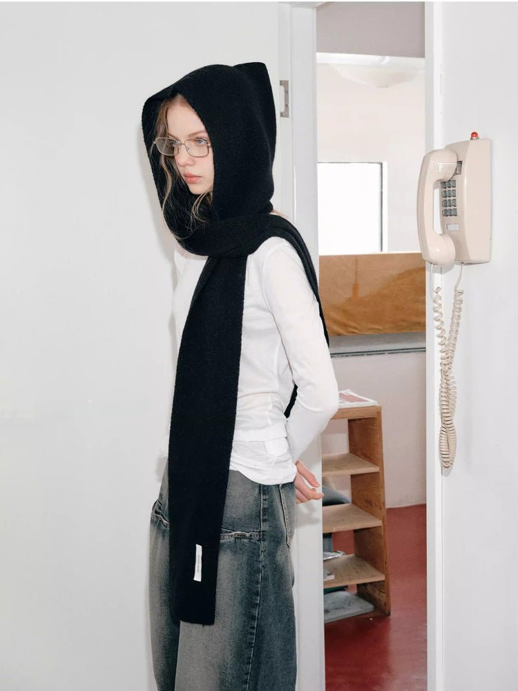 Woman wearing a black knit hooded scarf with a large bow detail