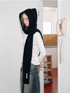 Woman in a black knit hooded scarf and long-sleeved white shirt