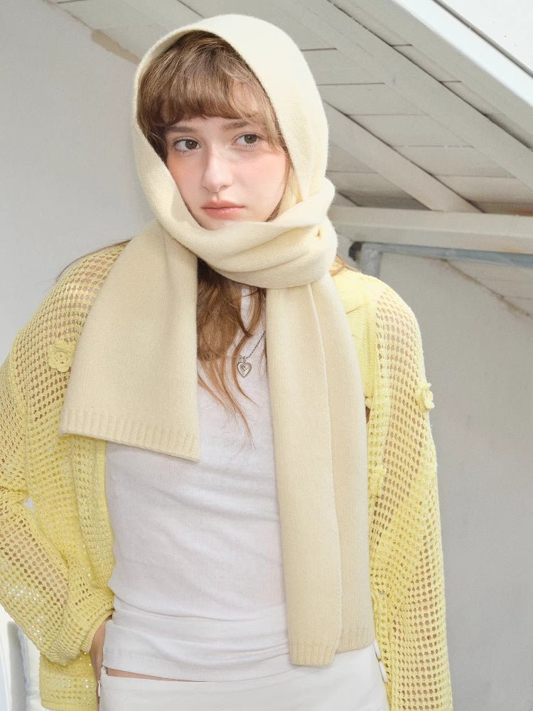 Cream knitted scarf worn as hood over head with yellow mesh cardigan and white top