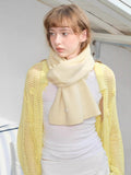Cream knitted scarf wrapped around neck with yellow mesh cardigan and white top