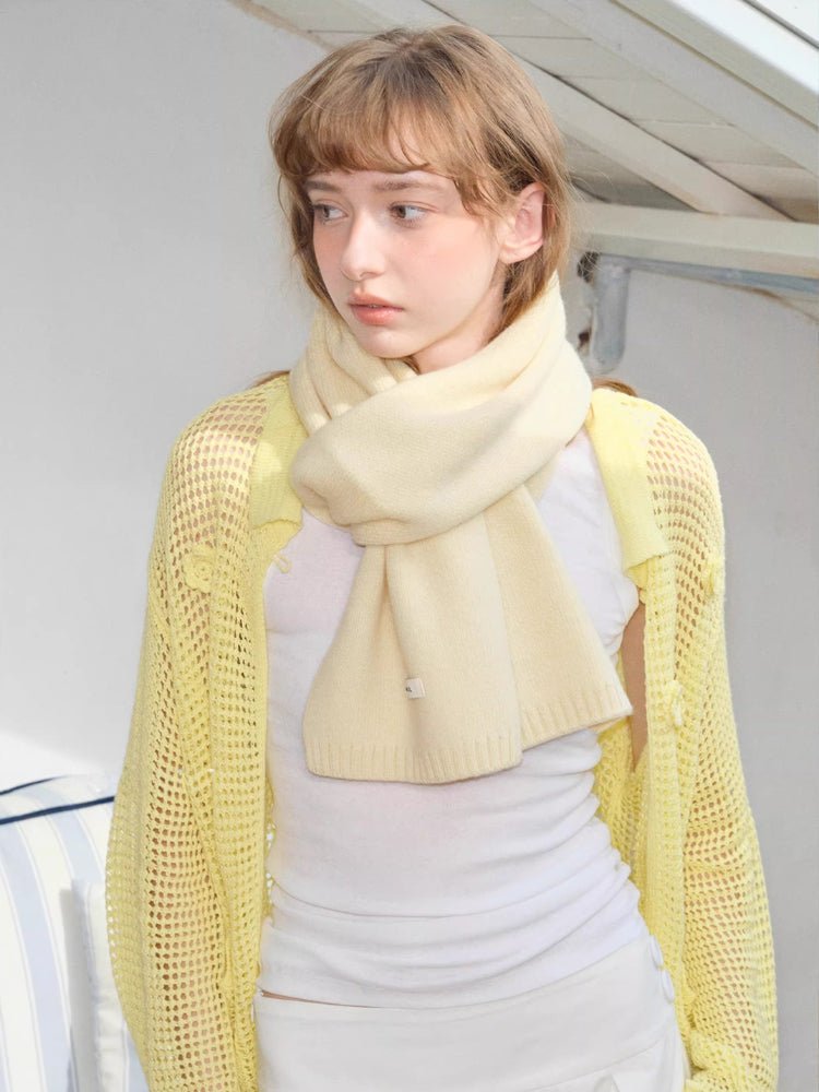 Cream knitted scarf wrapped around neck with yellow mesh cardigan and white top