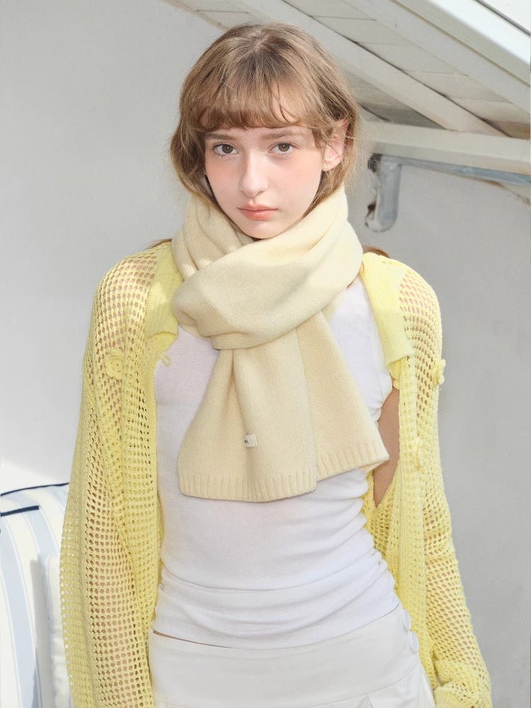 Cream knitted scarf styled around neck with yellow mesh cardigan and white top