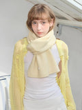 Cream knitted scarf styled around neck with yellow mesh cardigan and white top