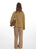 Back view of a woman in an oversized camel knit sweater and brown wide-leg jeans.