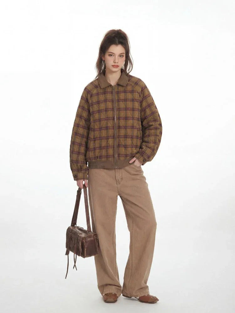 Woman in a brown and purple plaid bomber jacket with a collared neckline and button closure, holding a brown handbag.