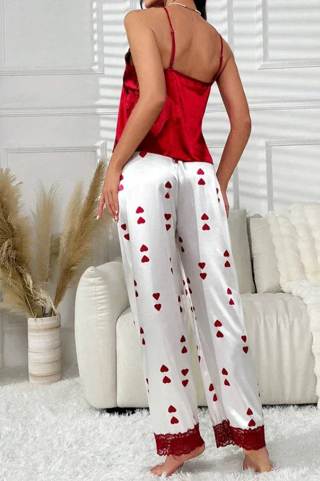 Back view of a woman wearing a red satin camisole and white satin pajama pants with a red heart print.