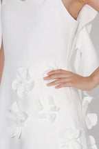 Close-up of the 3D floral appliqués on the bodice of a white A-line dress.