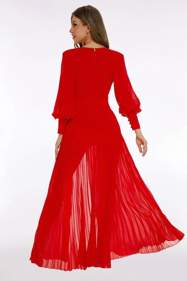 Back view of a woman in a red chiffon evening gown with bishop sleeves and a pleated skirt.