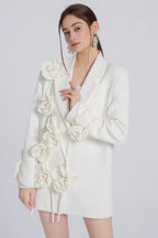 Woman wearing a white blazer with floral appliqués on the left shoulder and down the front.