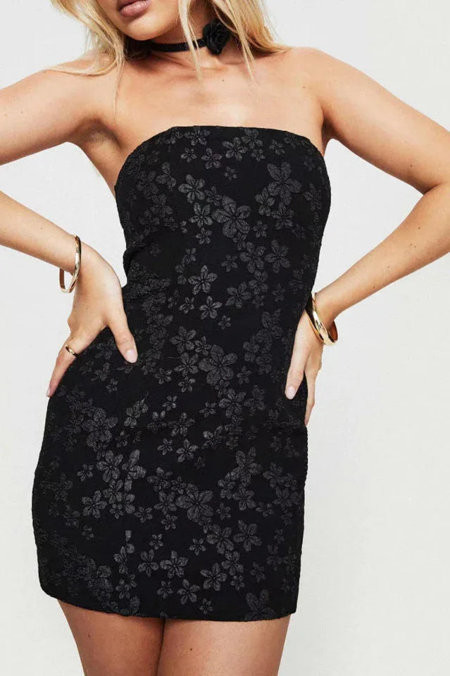 Woman wearing a black strapless floral jacquard mini dress, hands on hips