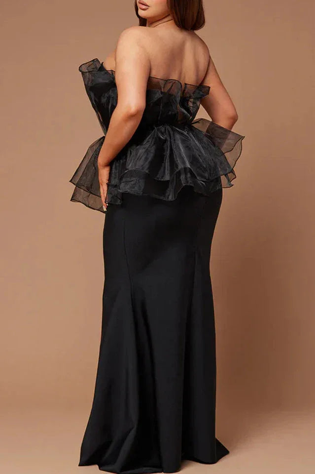 Rear view of plus-size woman in black strapless formal dress with ruffled organza peplum and mermaid skirt