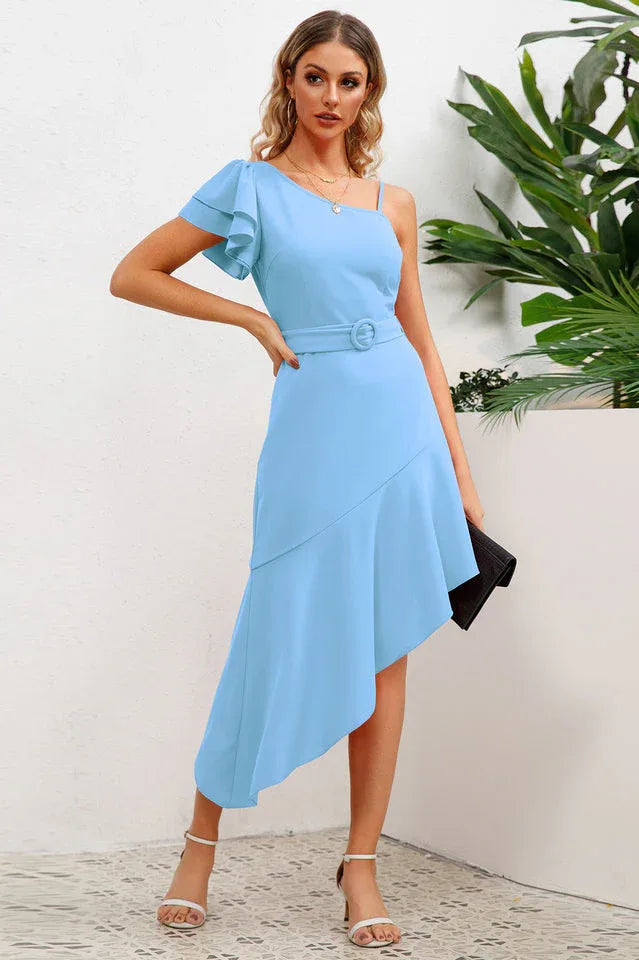 Woman in a light blue asymmetrical dress with a matching belt, holding a clutch