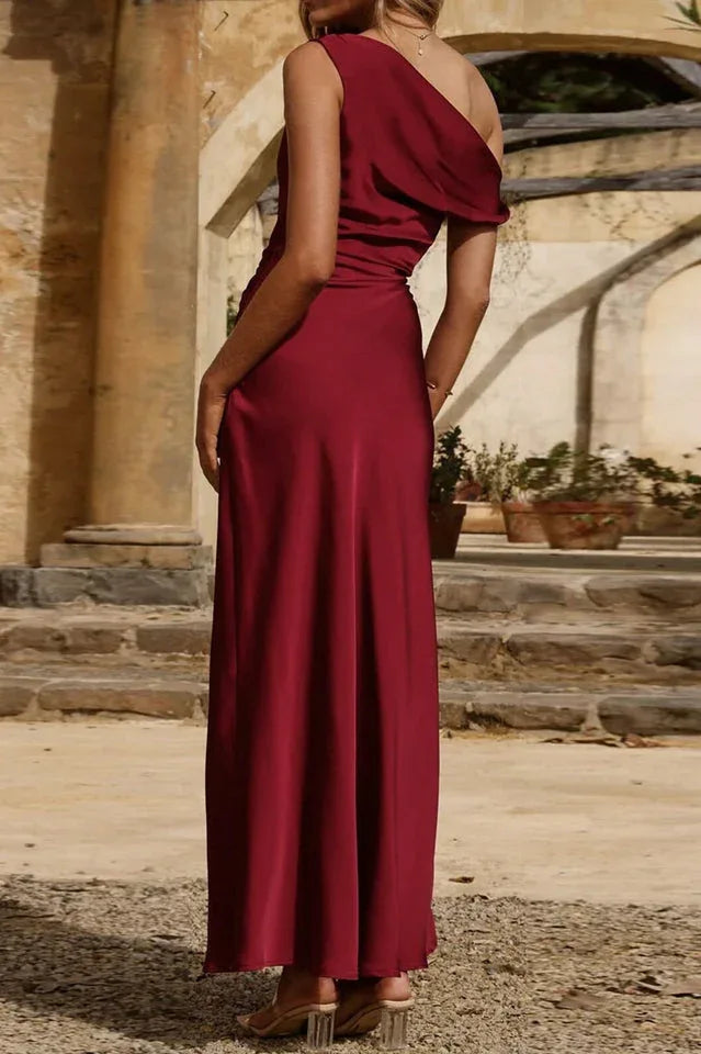 Back view of a woman in a burgundy satin column dress with a one-shoulder neckline.