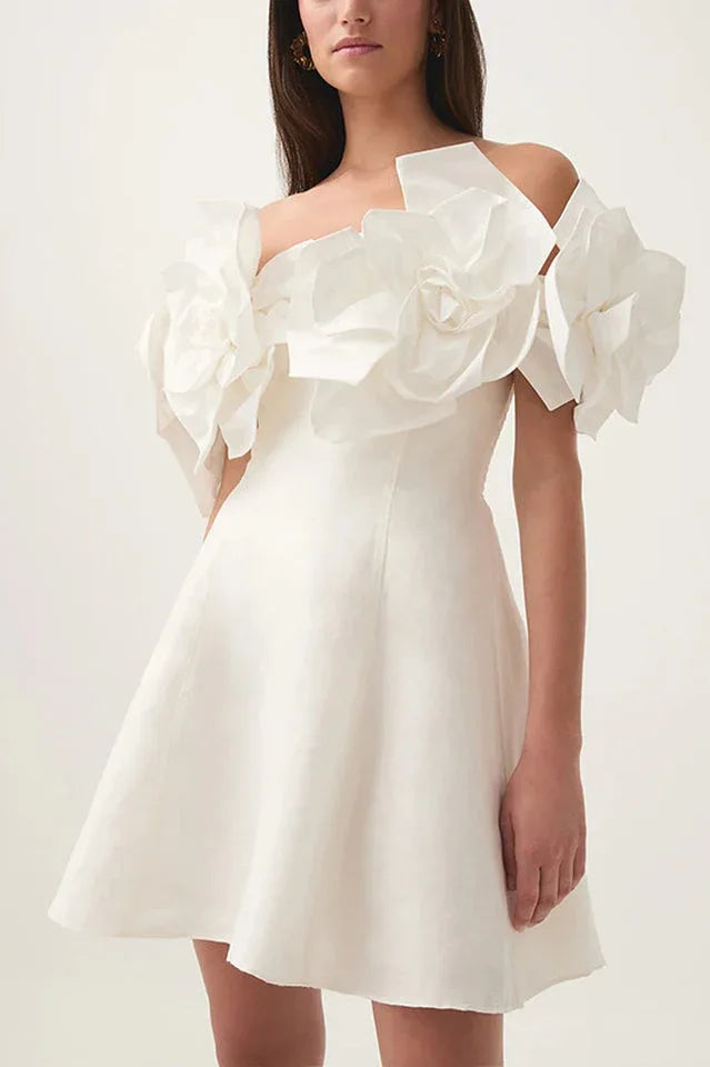 Woman modeling a white off-the-shoulder dress featuring striking floral appliques on the sleeves and a short, flared hem.