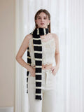 Woman wearing a black and white striped knit scarf with ruffle edges