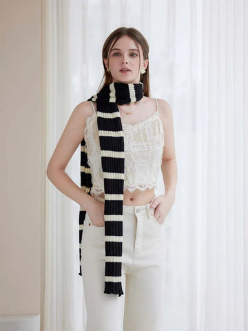 Woman wearing a black and white striped knit scarf with ruffle edges