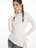 Model showing off the neckline and sleeves of a white long sleeve top.
