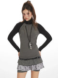 Close-up front view of a woman wearing a grey long-sleeved turtleneck top with black raglan sleeves and a pendant necklace.