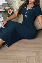 Woman sitting on the floor wearing a dark blue ribbed knit midi dress with white contrast trim and lace-up neckline.