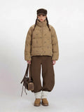Woman wearing a tan corduroy puffer jacket with a dog print and brown wide-leg pants.