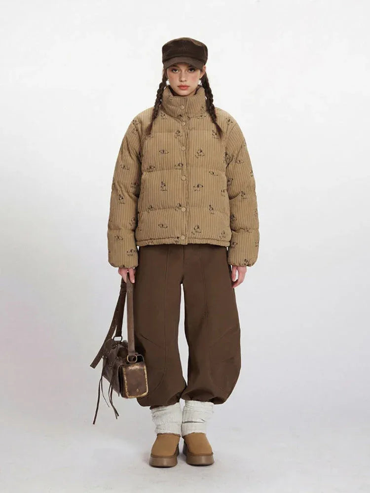 Woman wearing a tan corduroy puffer jacket with a dog print and brown wide-leg pants.
