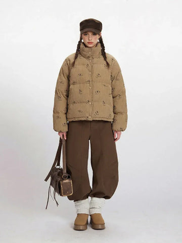 Woman wearing a tan corduroy puffer jacket with a dog print and brown wide-leg pants.