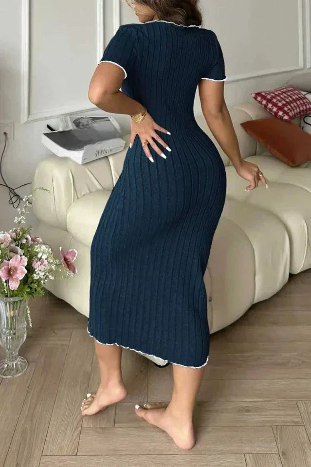 Rear view of a woman in a dark blue ribbed knit midi dress with white contrast trim.