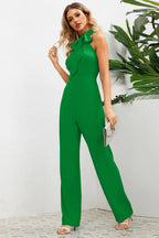 Front view of a green wide leg halter neck jumpsuit with a bow