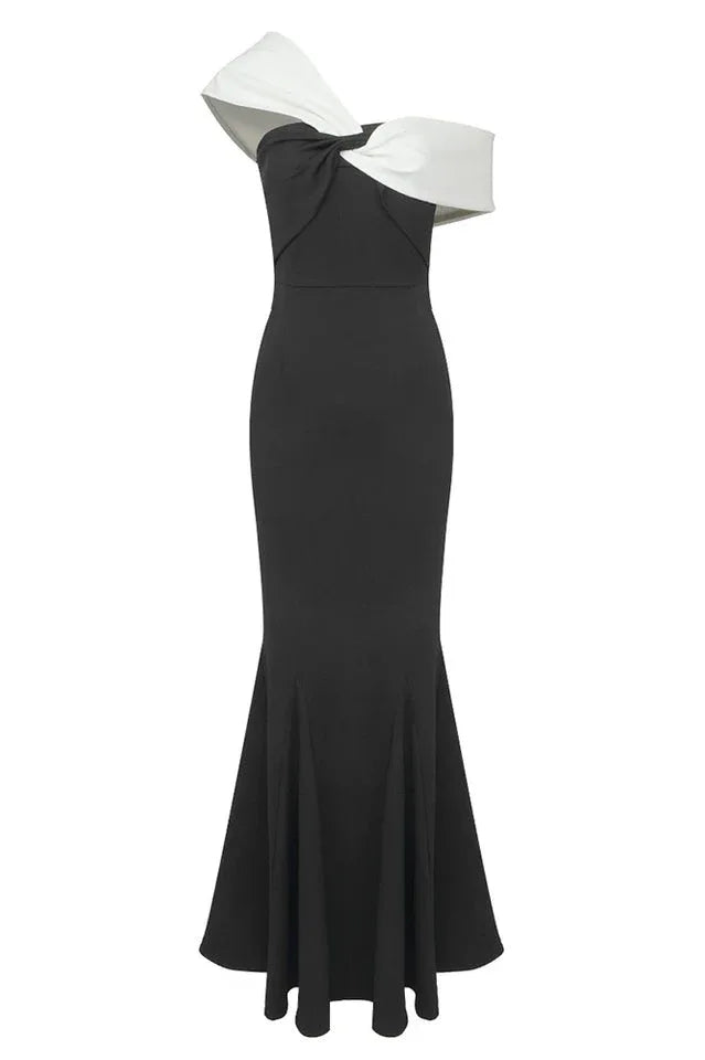 Model showcasing a black and white formal gown featuring an asymmetrical off-the-shoulder neckline