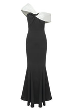 Model showcasing a black and white formal gown featuring an asymmetrical off-the-shoulder neckline