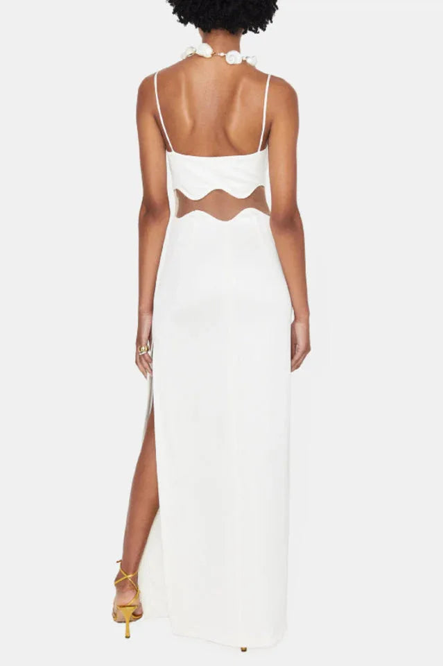 Back view of a woman in a white evening gown showing spaghetti straps and scalloped waist cutout