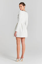 Rear view of a woman in a white long-sleeved dress with a crystal-embellished neckline and pleated skirt