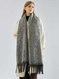 Full body shot of a woman in a coat and a long, grey scarf with fringe.