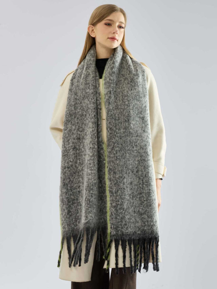 Full body shot of a woman in a coat and a long, grey scarf with fringe.