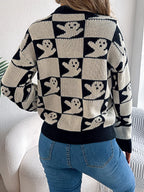 Back view of a woman wearing a black and cream checkerboard knit sweater with ghost print and blue jeans.