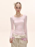 Close-up of a model's torso showing the details of a light pink long-sleeve square neck top.