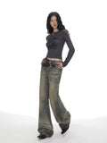 Full body shot of a woman in a grey long-sleeve graphic print cropped top and wide-leg jeans.