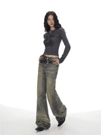 Full body shot of a woman in a grey long-sleeve graphic print cropped top and wide-leg jeans.