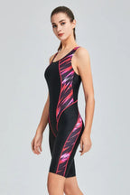 Side view of a woman in a black and pink patterned full-coverage athletic swimsuit