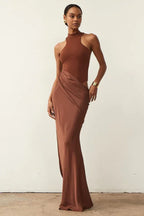 Woman wearing a brown satin column gown with a halter neckline and a draped skirt.