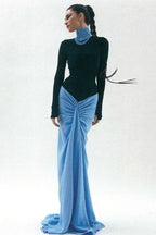 Woman in black long sleeve bodysuit and blue ruched maxi skirt with train