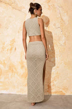 Woman wearing a beige knit crop top and a matching beige knit maxi skirt with a thigh-high slit, back view.