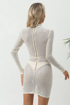 Back view of a woman in a sheer white rhinestone mini dress with a back zipper and tie waist.