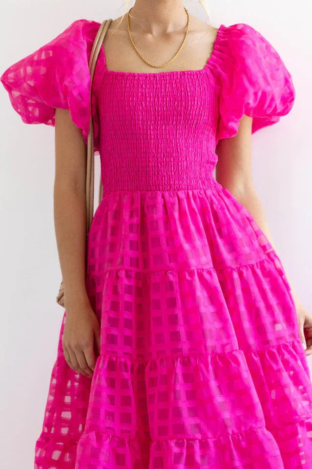 Close-up of the smocked bodice and checkered fabric of a fuchsia midi dress.