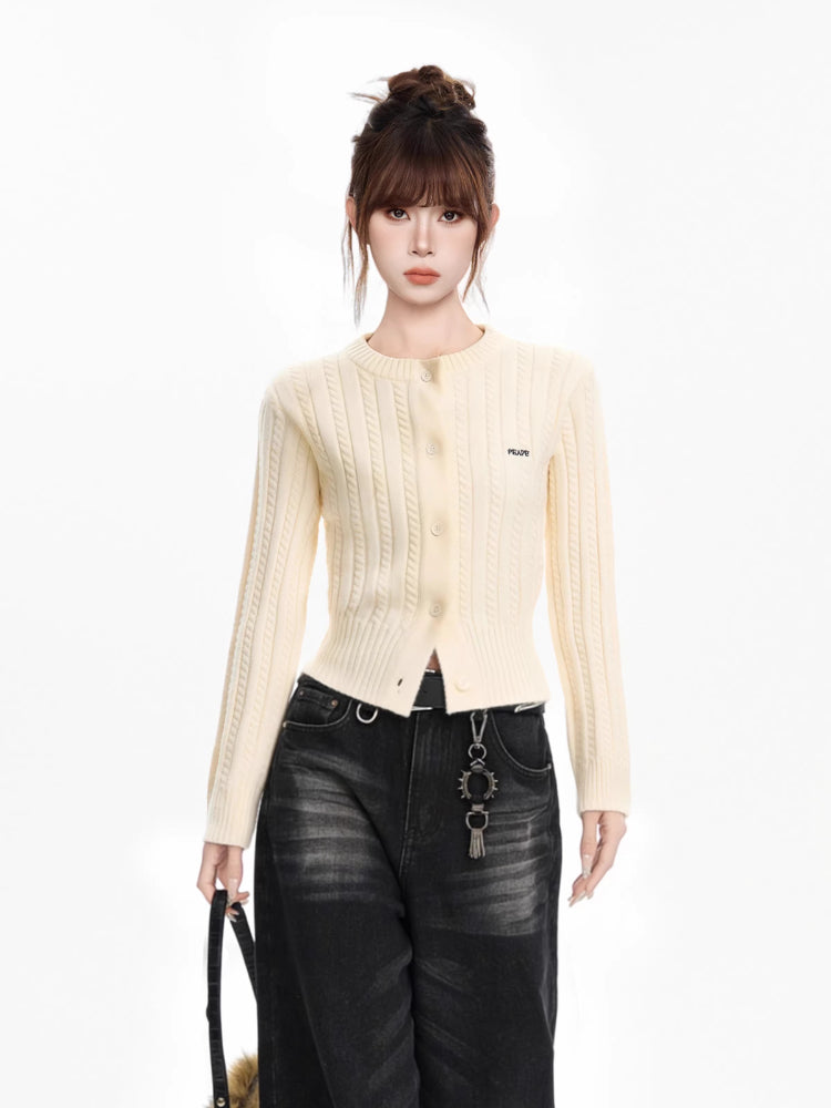 Full body shot of a woman in a cream cable knit cropped cardigan, dark wash wide-leg jeans, and accessories.
