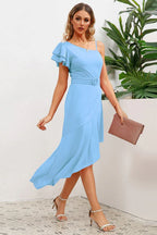 Full shot of a woman in a light blue one-shoulder dress with ruffled sleeve and asymmetrical skirt