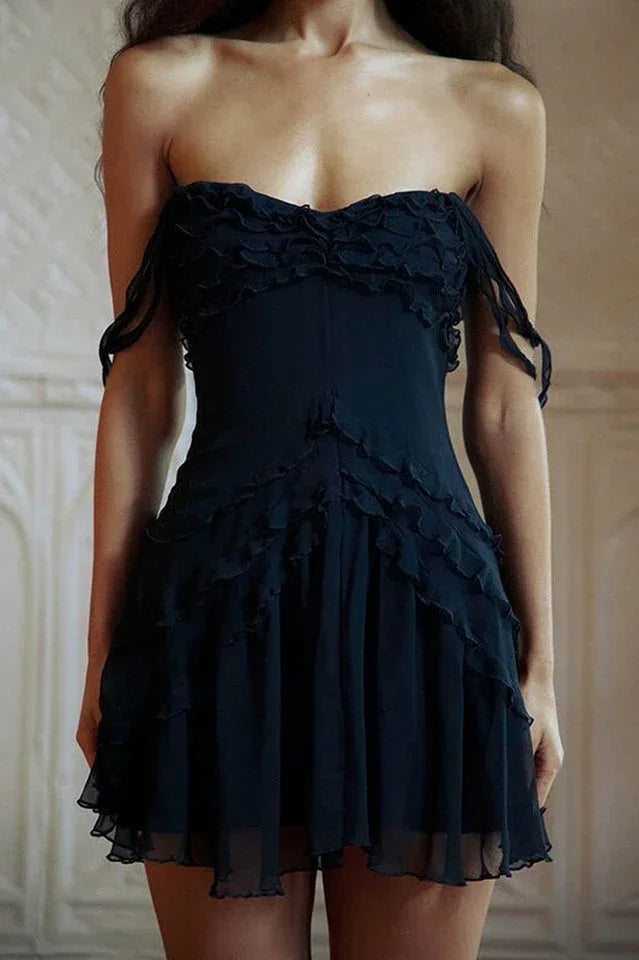 Front view of a woman in a black off-the-shoulder ruffled chiffon dress