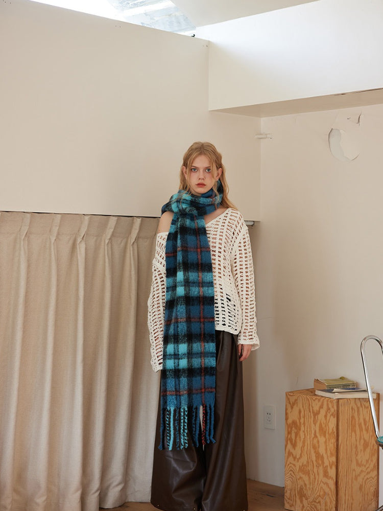 Model wearing blue plaid scarf with fringed ends