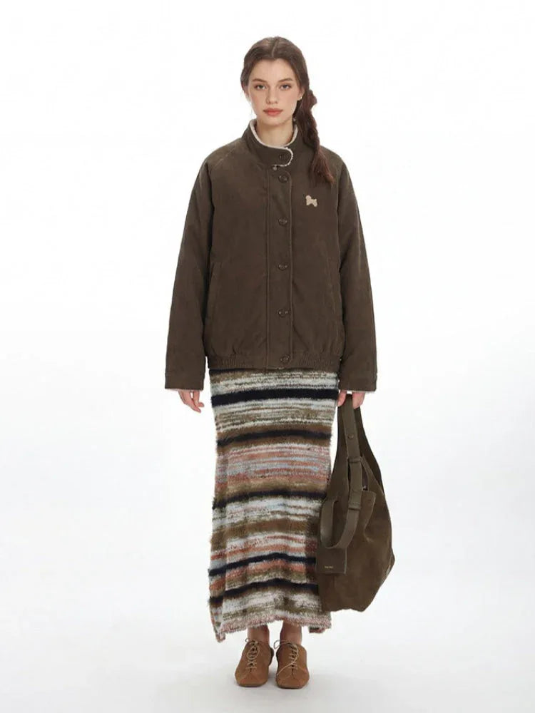 Woman wearing a brown quilted corduroy bomber jacket with a stand collar and embroidered detail