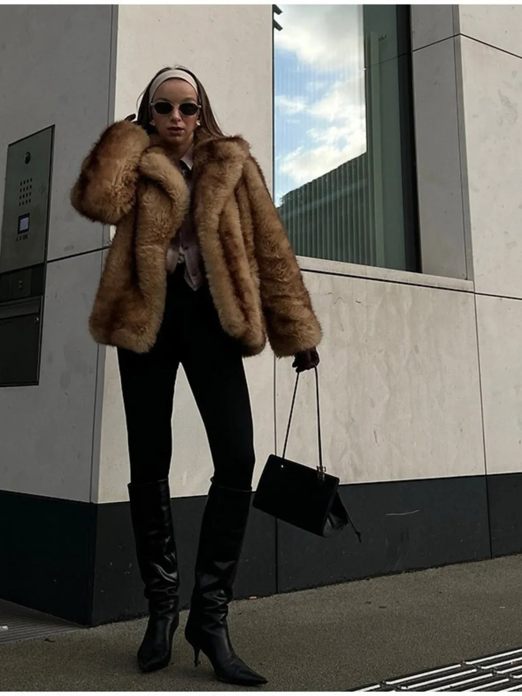fashionable woman posing in a faux fur coat with black trousers and boots